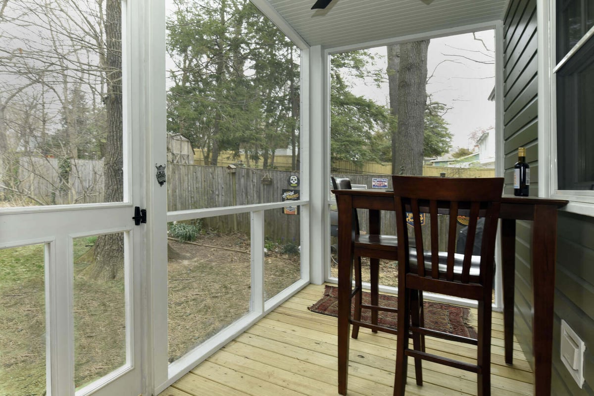 Screened porch with natural wood flooring overlooking a fenced backyard in a remodeled home by Villa Builders in Annapolis, MD