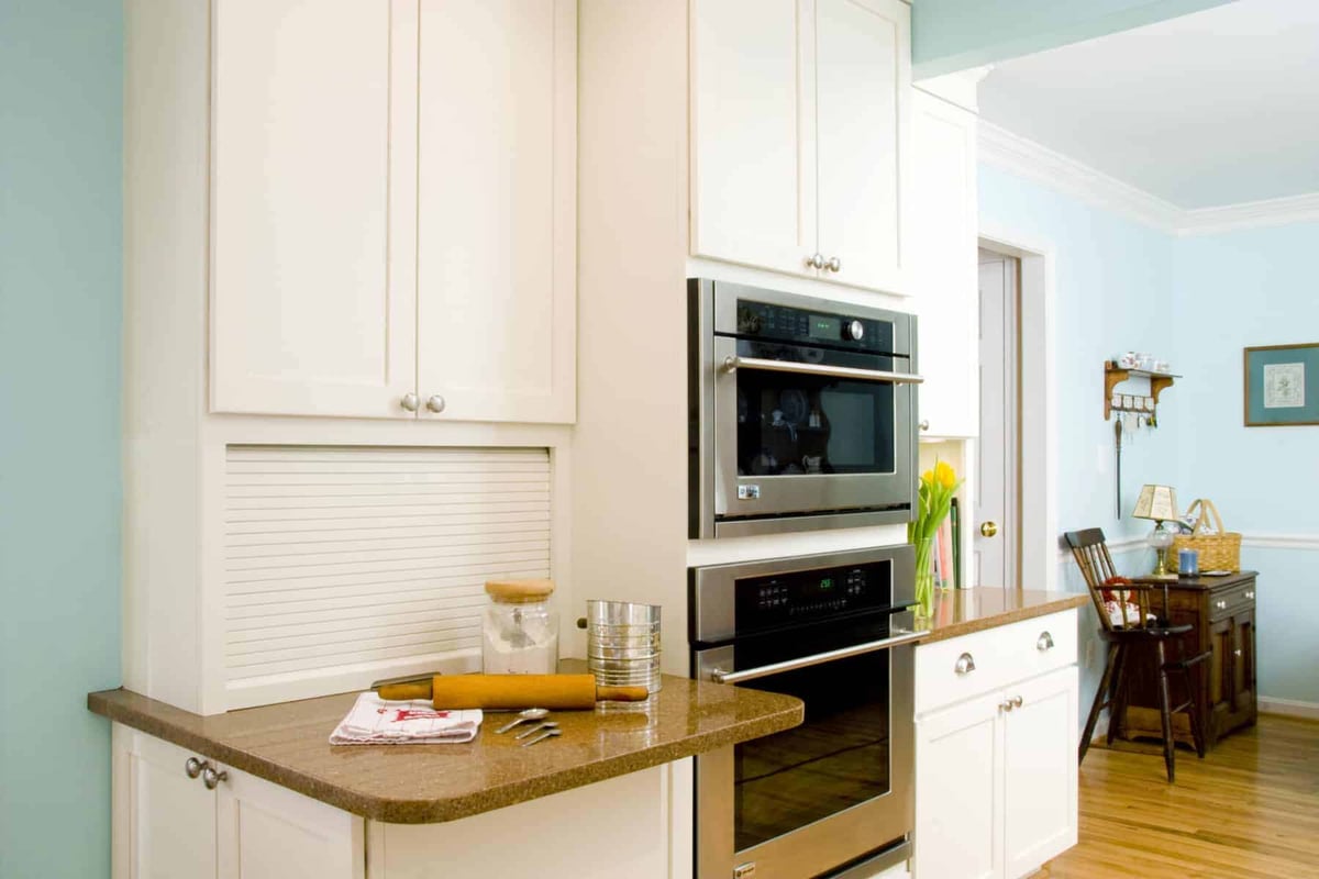 Modern kitchen with white cabinetry, built-in stainless steel appliances, and a small baking station by Villa Builders in Annapolis, Maryland