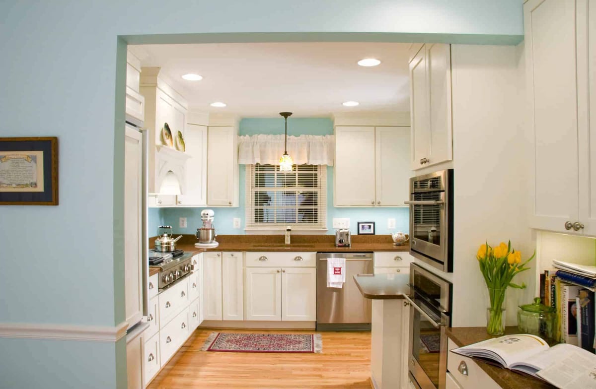 Spacious kitchen with white cabinets, stainless steel appliances, and a central window by Villa Builders in Annapolis, Maryland